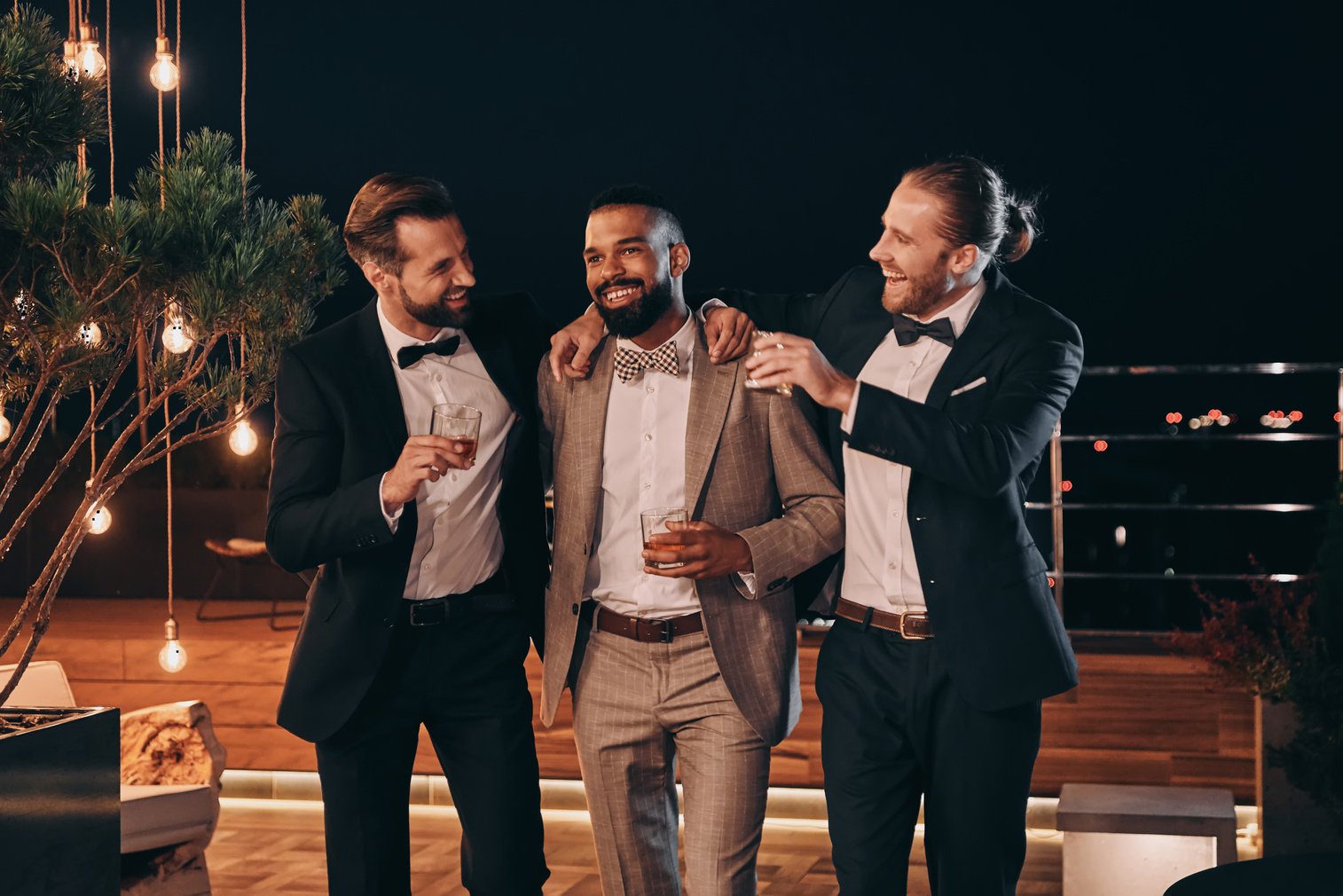 Three handsome men in suits drinking whiskey and communicating